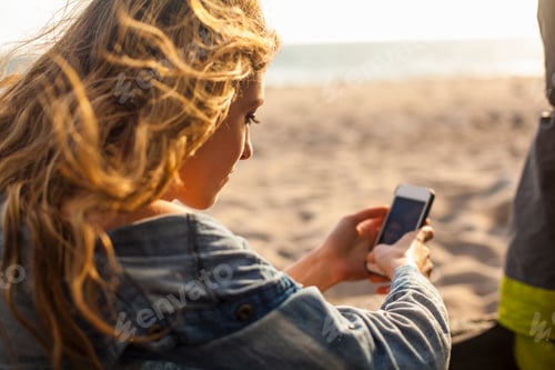 Preview: Woman using smartphone on beach