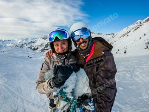 Preview: Happy couple enjoying winter snowboarding vacation in mountains