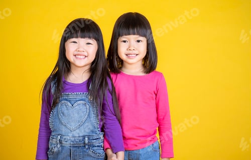 Preview: Portrait of young happy little asian girls in on yellow background with copy space