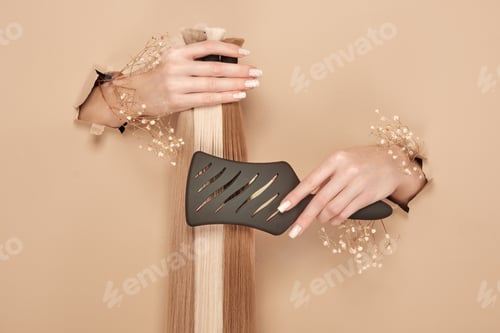 Preview: Hands with flowers hold strands of hair for extensions on a beige background.