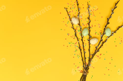 Preview: Willow twigs on a yellow background. Easter eggs are lying nearby. Copy space