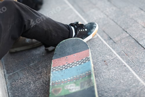 Preview: Young boy sitting with skateboard in city