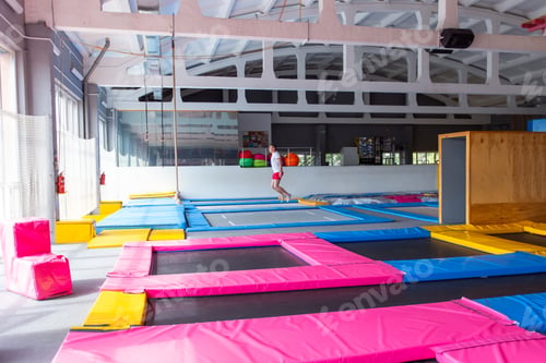 Preview: Fitness, fun, leisure and sport activity concept - Handsome happy man jumping on a trampoline