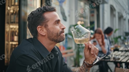 Preview: Bearded guy tasting wineglass open air restaurant closeup. Man enjoying alcohol