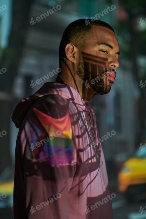 Vista previa: trendy african american male model posing in profile in digital projector lights, fashion concept