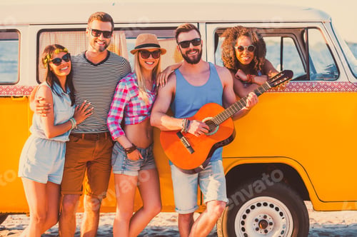 Preview: Friends forever. Group of young cheerful people standing near their retro minivan and smiling