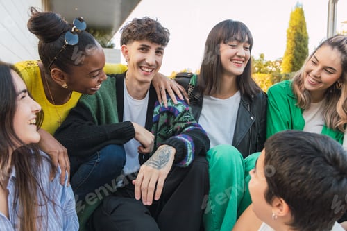 Preview: Cheerful group of diverse friends sitting in daylight on building stairs