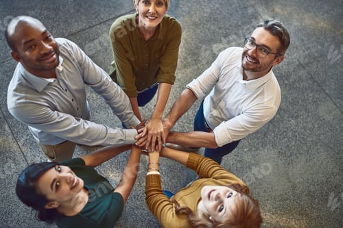 Preview: High angle portrait of a group of colleagues joining their hands in solidarity at work