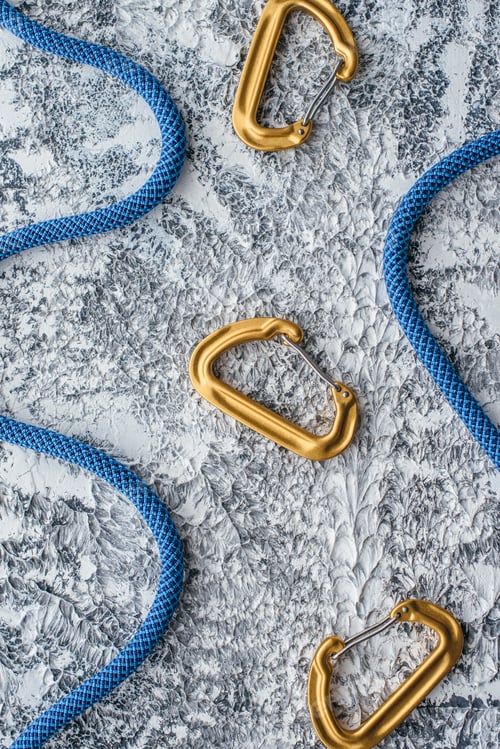 Preview: Isolated photo of climbing equipment. Part of carabiner lying on the white and grey colored table