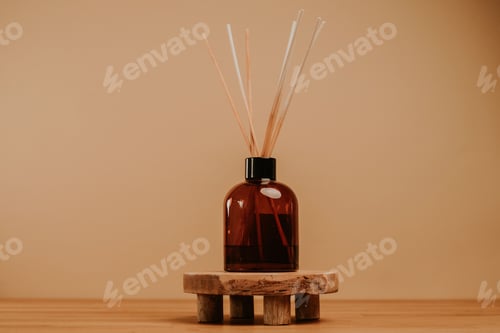 Preview: Essential oil diffuser with sticks standing on wooden platform. Beige background. Copy space.