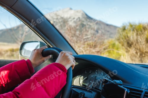 Preview: Woman hands holding steering wheel with mountains in the background