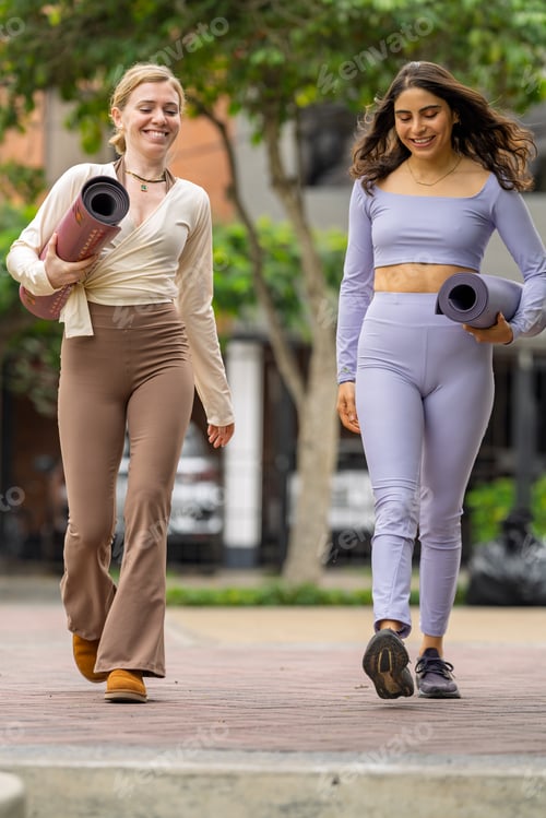 Preview: Women carrying yoga mats walking in urban park promoting health and relaxation