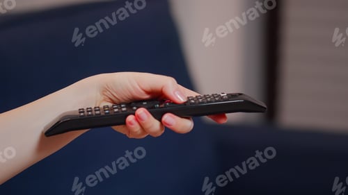 Preview: Close up of caucasian hand with TV remote switching channels