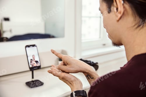 Preview: Mid adult man using sign language in front of smartphone