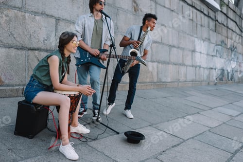 Preview: Young happy woman with drum and men with guitar and djemba at city street
