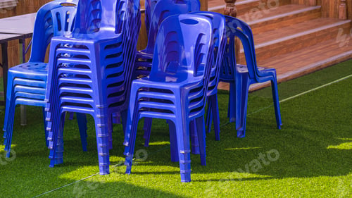 Preview: Group of plastic chairs and foldable table on artificial turf outside of building for outdoors event