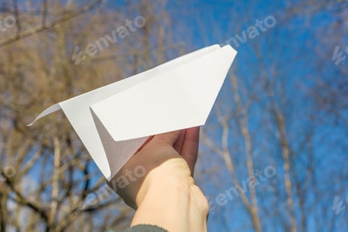 Preview: Abstract paper plane in hand, blue sky, spring trees sun background