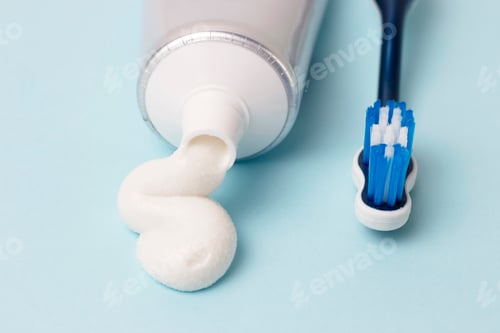Preview: Toothpaste in tube and toothbrush on blue background. Dental hygiene concept.
