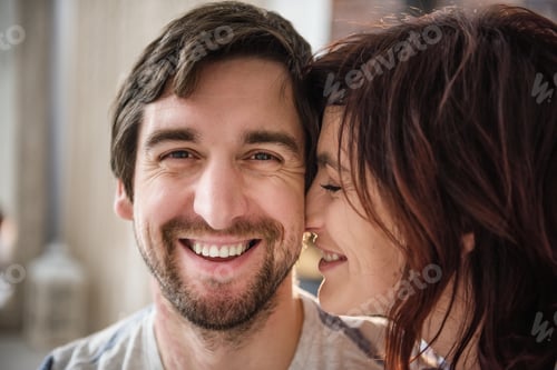 Preview: Close-up portrait of a young adult couple in love. A beautiful girl kisses a man on the cheek,