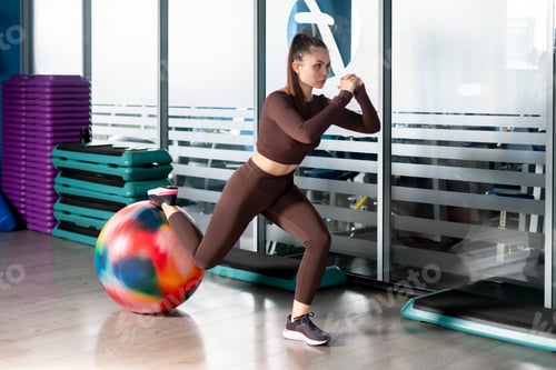 Preview: a young female athlete doing exercises on a big rubber ball in a gym