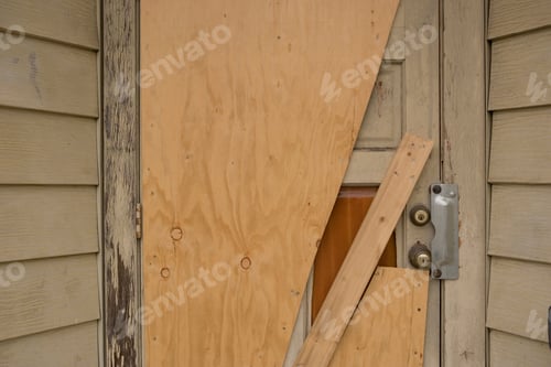 Preview: A boardedup door on a weathered wooden house
