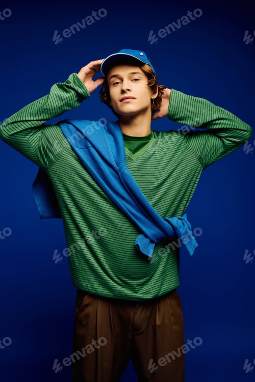 Preview: Fashionable young man showcases modern street style against a vivid blue backdrop