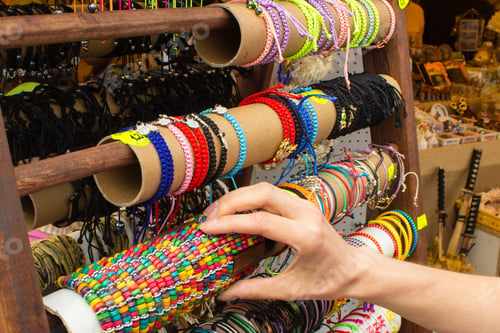 Preview: Hand of woman with colorful bracelets on stall at bazaar