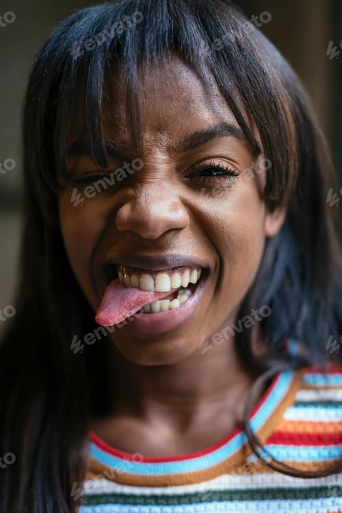 Preview: Portrait of laughing young woman sticking out tongue