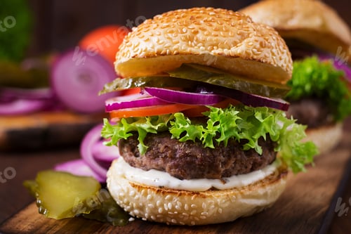 Preview: Big sandwich - hamburger burger with beef, pickles, tomato and tartar sauce on wooden background.