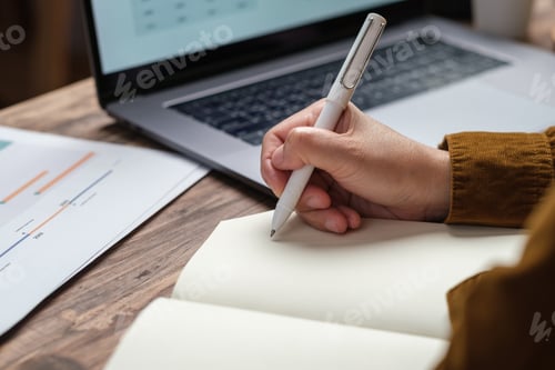 Preview: close uop woman hand writing on notebook at worknig desk at home