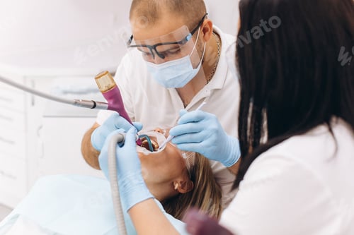 Preview: A dentist in a mask and goggles treats a woman's teeth.