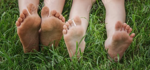 Preview: Children's legs on green grass. Selective focus.