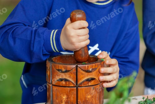 Preview: Child grinds aromatic herbs in a mortar. Outdoor experience.
