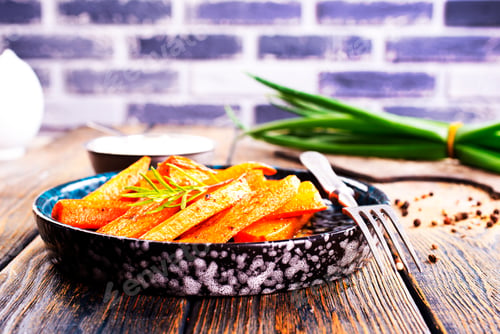 Preview: Fried carrots with green herbs in baking tray, close up