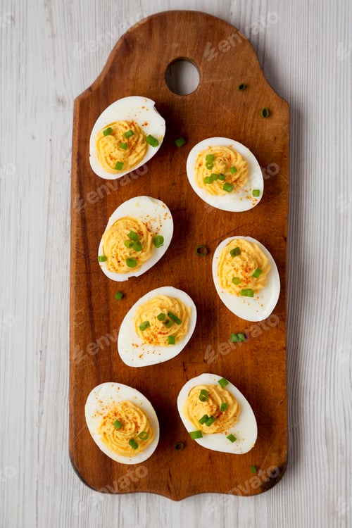 Preview: Homemade Deviled Eggs with Chives on a rustic wooden board on a white wooden background