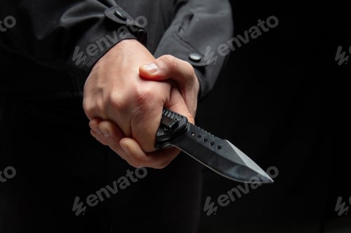 Preview: Criminal holding a knife with both hands closeup, armed attack concept.
