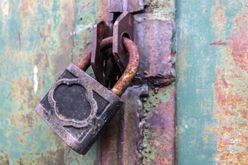 Preview: old and rusty padlock with scratches locks the steel doors of an abandoned vault