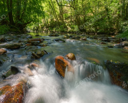 Preview: River flows between orange boulders and green oak and birch forests