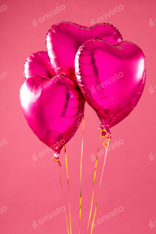 Vista previa: Vertical of four shiny pink heart shaped balloons floating on white background with copy space