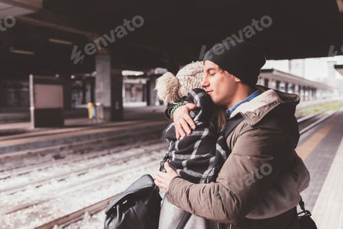 Preview: couple standing in train station and embracing
