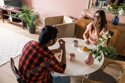 Preview: Happy indian couple having breakfast and small talk together in the kitchen - friendship, dating and