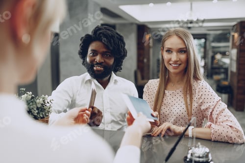 Preview: Business trip concept. Black man and caucasian woman businesspeople colleagues checking-in in hotel