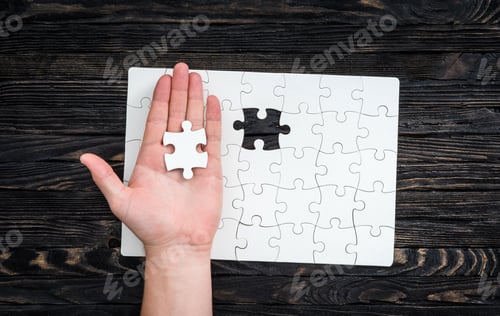Preview: hand with the last piece of white uncomleted puzzle