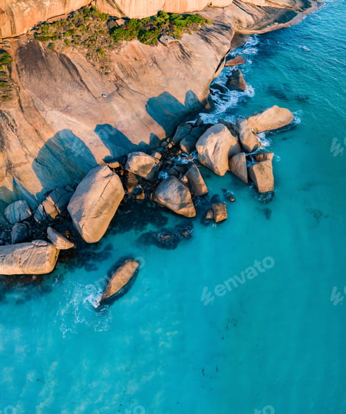 Preview: Vertical aerial view of a rocky seashore with clear blue water