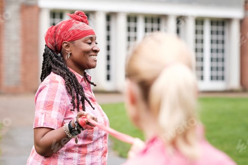Preview: Two women friends using a resistance band outdoors.