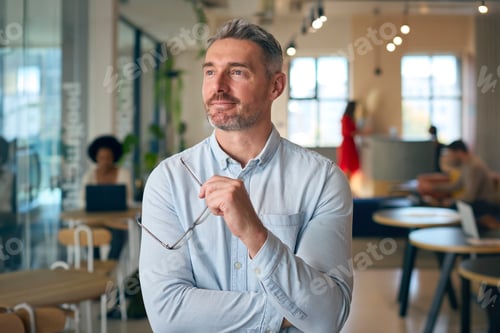 Preview: Portrait Of Smiling Mature Businessman Holding Glasses Standing In Busy Office