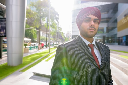 Preview: Portrait of Indian businessman outdoors in city with lens flare