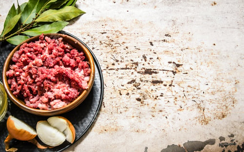 Preview: Minced meat in a wooden bowl with spices and oil.