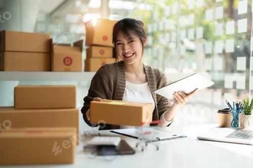 Preview: Young woman small business owner online shopping at home. checking orders from customers with