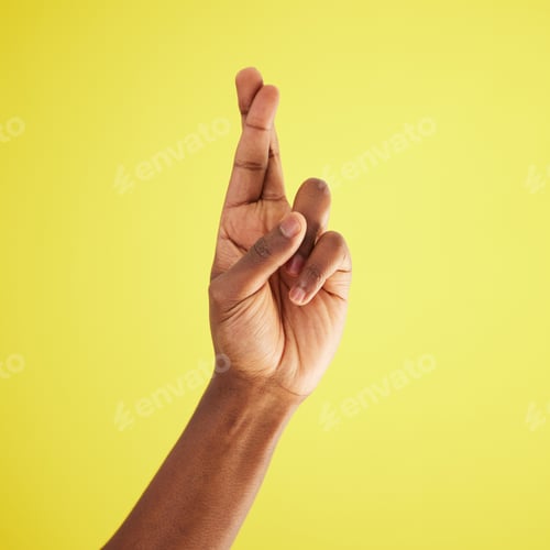 Preview: Studio shot of an unrecognisable man crossing his fingers against a yellow background